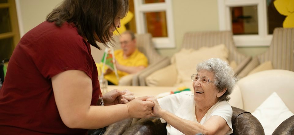 A caregiver helping an older woman walk with a walker