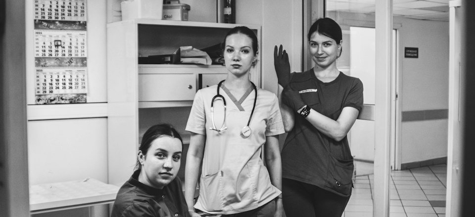 Three healthcare professionals in scrubs in a clinic hallway