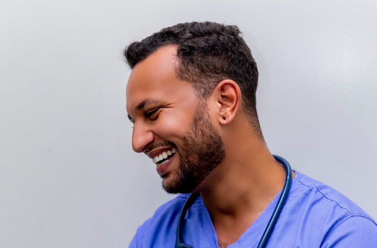 A smiling nurse in blue scrubs with a stethoscope